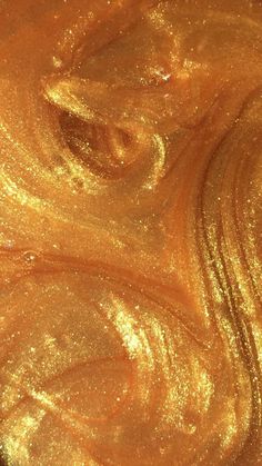 an orange liquid with gold flecks is shown in this close up photo,