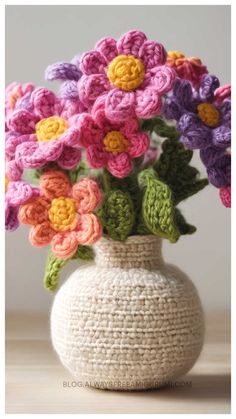 crocheted flowers in a white vase with green leaves and pink, purple, yellow and orange flowers