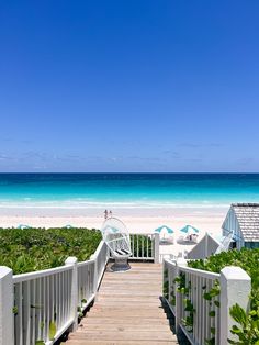 a wooden walkway leading to the beach with umbrellas