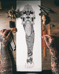 a person with tattoos on their arms and legs is holding a pencil in front of a drawing