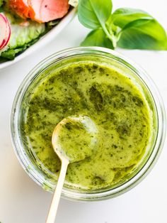 a bowl filled with green pesto next to a salad