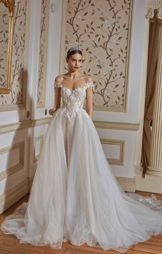 a woman in a white wedding dress standing on a wooden floor next to a mirror