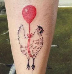 a chicken with a heart balloon tattoo on its leg is seen in this photo from the waist up