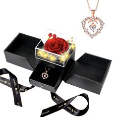 a box with a rose inside and two necklaces in it