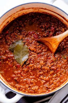 a pot filled with chili and a wooden spoon