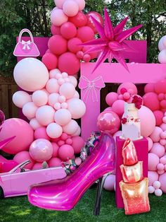 a bunch of balloons that are in the grass near a pink chair and some shoes