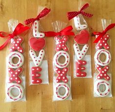 four decorated cookies in the shape of letters with bows and hearts on them sitting on a wooden surface