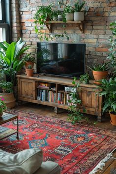 a living room filled with lots of plants next to a large tv mounted on a brick wall