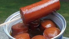 a hot dog on a stick in a can of ice water with some other food