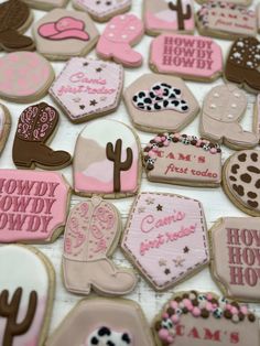 many decorated cookies on a table with cowboy and cowgirl designs in pink, brown, and white