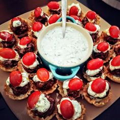 an assortment of appetizers on a platter with dip in the middle and toppings