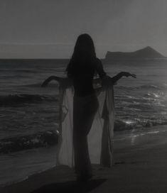 a woman standing on top of a beach next to the ocean