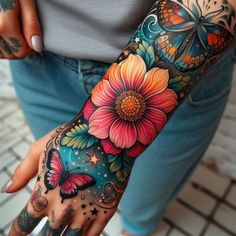 a woman's hand with colorful flowers and butterflies on the wrist, tattoo style