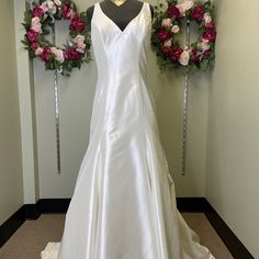 a wedding dress on display in front of two wreaths