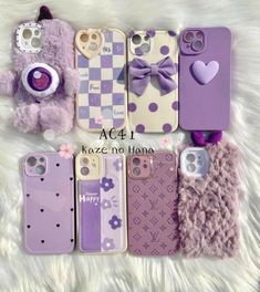 four cell phones with purple cases and a teddy bear in the middle one has a bow on it