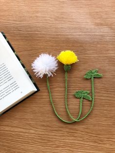 the book is next to two crocheted flowers and an open book on a table