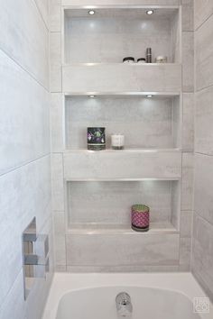 a white bathroom with shelves above the bathtub