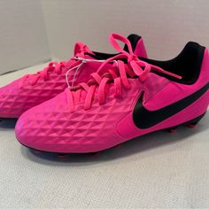 a pair of pink and black soccer cleats sitting on top of a white surface