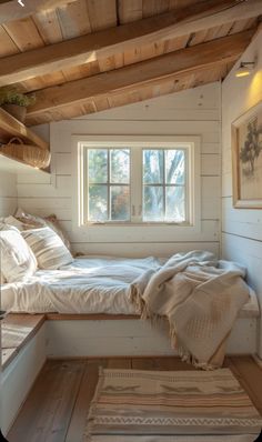 a bed sitting under a window in a bedroom next to a wooden floor and ceiling