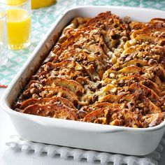 a casserole dish with meat and cheese on it, next to orange juice