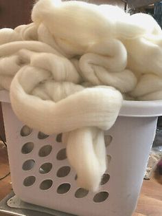 a basket filled with white yarn on top of a wooden table