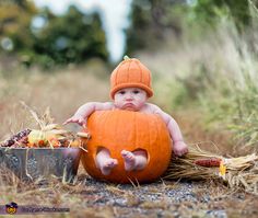 a baby sitting on top of a pumpkin in the middle of a field with corn