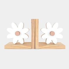 two white flower bookends sitting on top of a wooden shelf next to each other