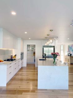 a large kitchen with white cabinets and wood flooring on the walls, along with an island in the middle