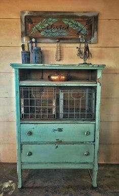 an old dresser with birdcages on top is painted blue and has a sign above it