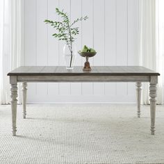 a wooden table with two vases and a plant on it in front of a white wall