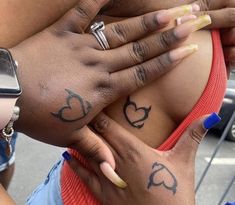 two women with tattoos on their stomachs holding onto each other's hands and fingers