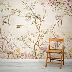 a chair sitting in front of a wall with flowers and birds on it