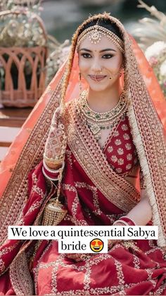 a woman sitting on top of a wooden bench wearing a red and gold wedding dress