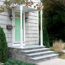 a house with steps leading up to the front door and green shutters on either side