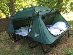 a tent that is in the grass with some blankets on it and two pillows inside