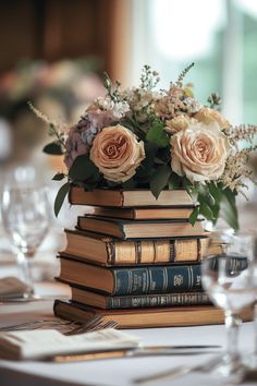 a stack of books sitting on top of a table covered in flowers and greenery