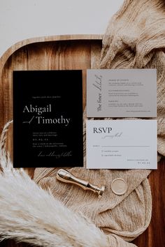 the wedding stationery is laid out on a wooden tray