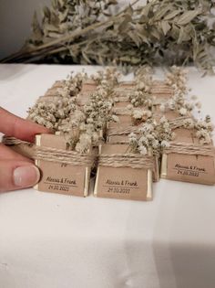 a hand is holding small tags with dried flowers on them