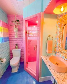 a bathroom with pink, blue and yellow colors on the walls next to a white toilet