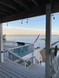 an american flag is hanging on the porch next to the pool and deck overlooking the water