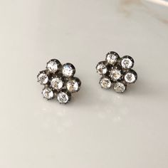 A Vintage pair of 9 carat gold and silver set paste (stones that mimic the look of diamonds) earrings. CONDITION: Good condition, wear consistent with age and use. Please see photos for more detail. CLUSTER DIAMETER: 13mm SETTING HEIGHT: 4mm PASTE DIAMETER: 3mm WEIGHT (BOTH): 3.7g (HZ/UCZ) Victorian White Gold Diamond Earrings With 17 Jewels, Victorian Diamond Earrings In White Gold With 17 Jewels, Dazzling Rose Cut Diamond Earrings For Formal Occasions, Classic Formal Earrings With Rose Cut Diamonds, Vintage Rose Cut Diamond Earrings For Anniversary, Classic Rose Cut Diamond Earrings For Evening, Classic Wedding Diamond Earrings With Screw Back, Victorian Diamond White Diamond Earrings For Formal Occasions, Victorian Diamond White Earrings For Formal Events