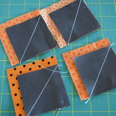 four pieces of fabric laid out on top of a cutting mat with scissors and thread