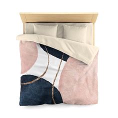 a bed with a pink and blue comforter next to a white pillow on top of it