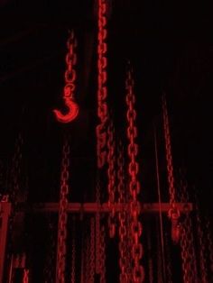 a clock is lit up in the dark with chains hanging from it's sides