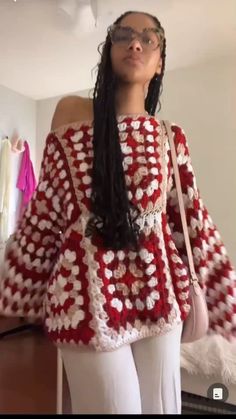 a woman standing in front of a mirror wearing a red and white crochet sweater