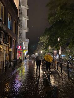 people walking down the street with umbrellas on a rainy night