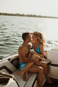 a man and woman sitting on the back of a boat in the water, kissing