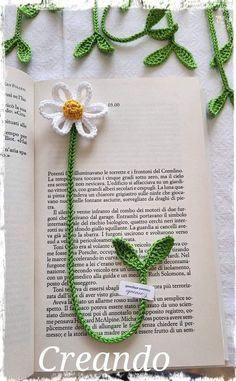 an open book with a crocheted flower attached to it and the words grando written in spanish