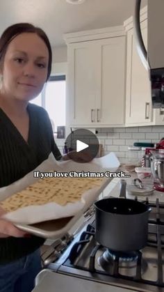 a woman holding a tray of crackers on top of a kitchen counter next to an oven