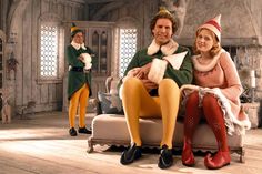 two people in elf costumes sitting on a couch with one person standing behind the other